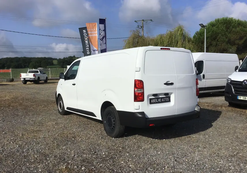 Vue 3/4 arrière droite d'un utilitaire Citroën Jumpy XL blanc, avec portes arrière fermées sur un parking extérieur.