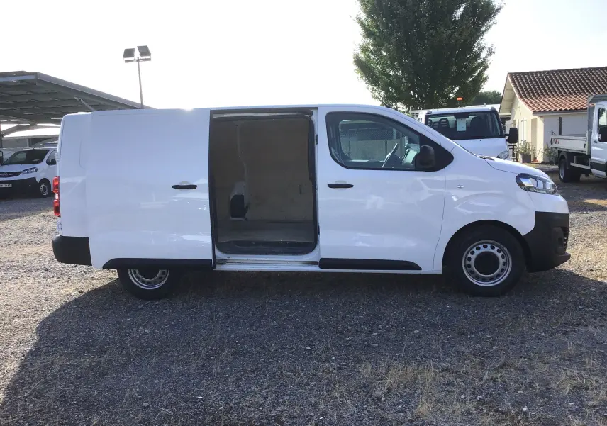 Vue latérale droite d'un utilitaire Citroën Jumpy XL blanc avec porte coulissante ouverte sur un parking extérieur.