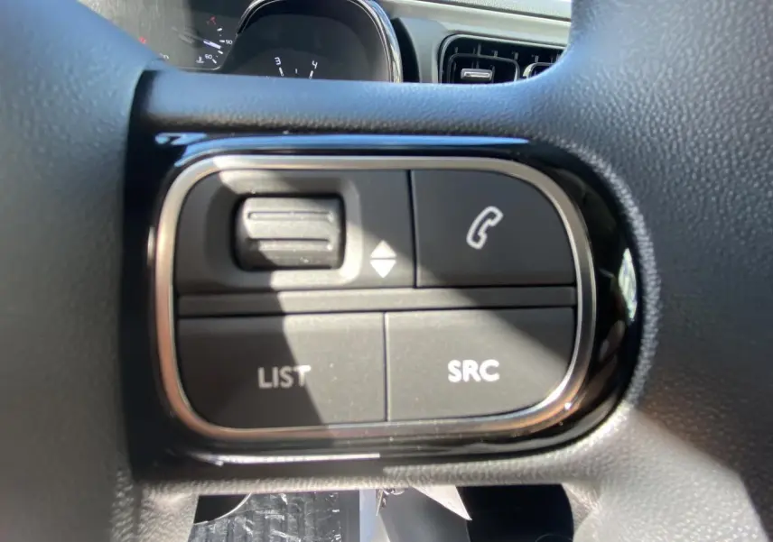 Gros plan sur les commandes audio au volant du Citroën C3 blanc 2022, avec boutons de téléphone et liste SRC visibles.