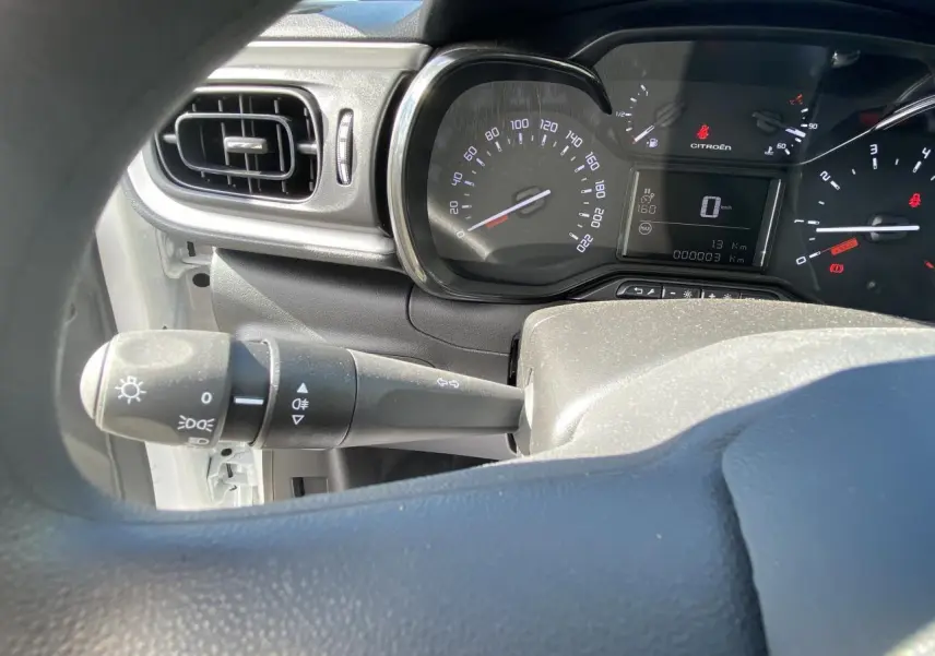 Vue rapprochée du tableau de bord et du compteur de la Citroën C3 blanche de 2022 avec commandes d'éclairage visibles.