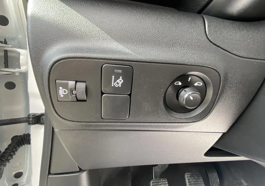 Panneau de commandes côté gauche avec réglage des phares et rétroviseurs dans une Citroën C3 blanche 2022.