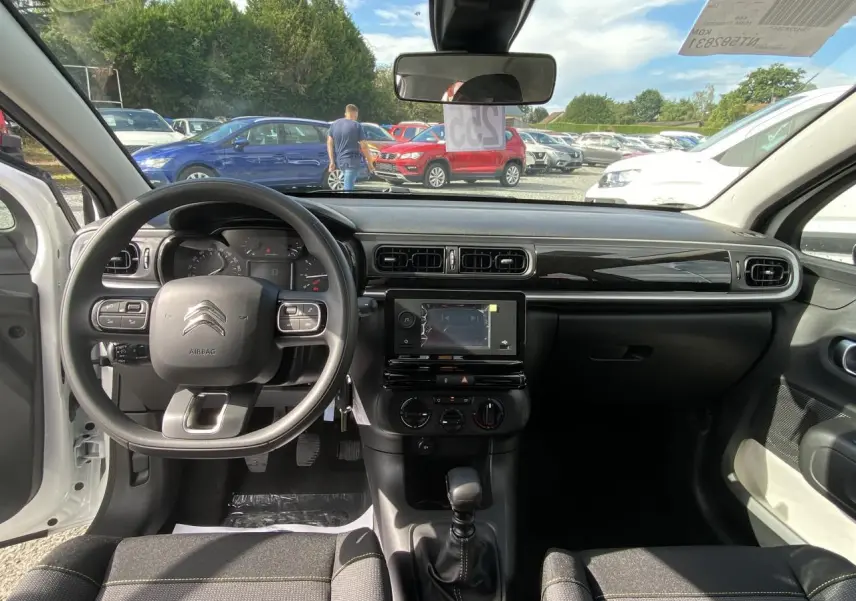 Intérieur de la Citroën C3 2022 blanc Banquise, vue du poste de conduite avec tableau de bord et volant multifonction.