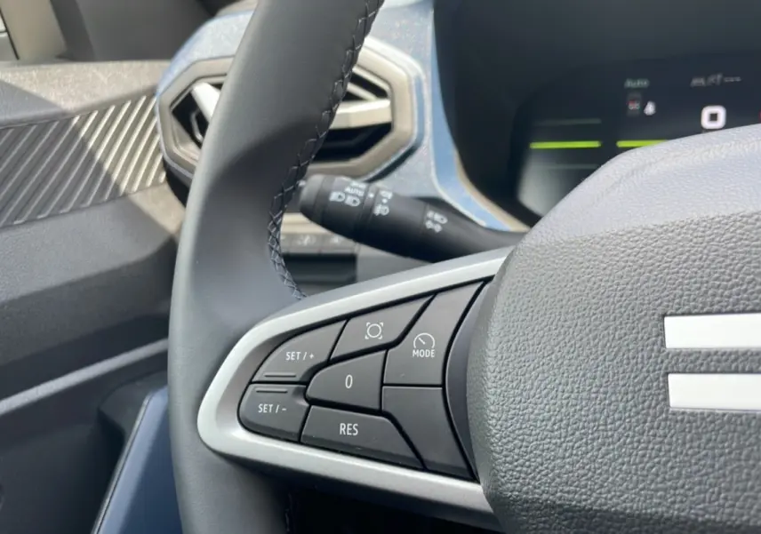 Gros plan sur le volant du Dacia Bigster 2025, montrant les commandes de régulateur et l'air vent hexagonal côté gauche.