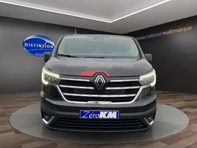 Vue frontale d'un Renault Trafic Cabine Approfondie noir 2025 avec calandre chromée et phares allumés en intérieur showroom.
