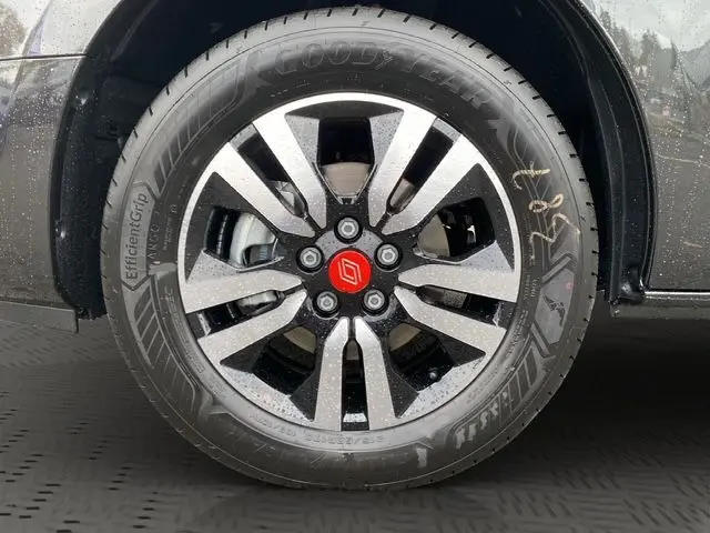 Gros plan sur la jante alu noire à motifs argentés d’un Renault Trafic noir 2025, avec pneu Goodyear humide.
