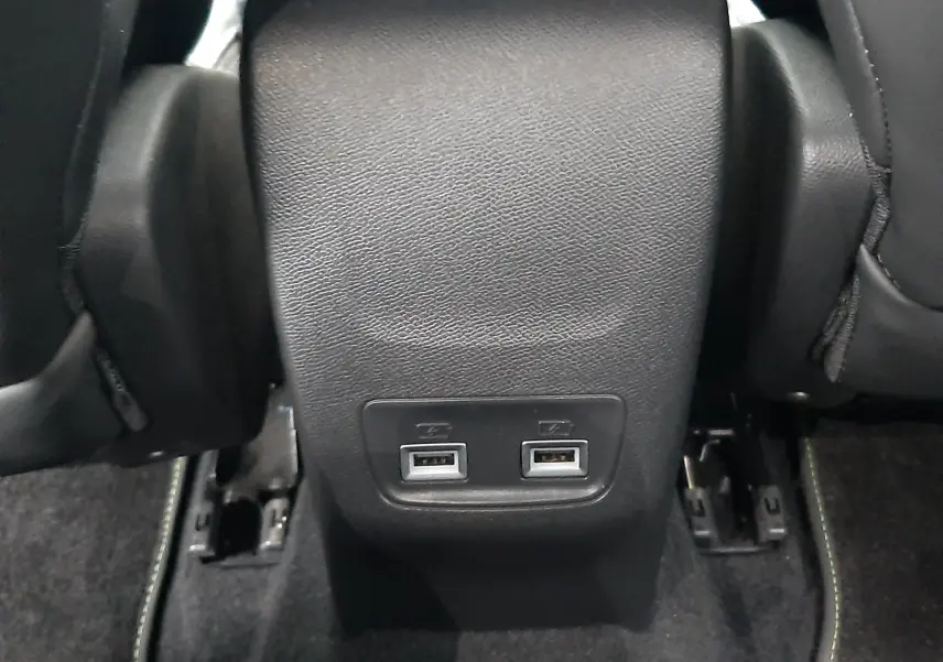 Prise USB double en gros plan sur la console arrière noire du Peugeot 2008 2023 blanc nacré toit noir.