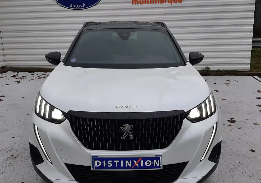 Vue avant d'un Peugeot 2008 blanc nacré avec toit noir, phares allumés et calandre noire distinctive.