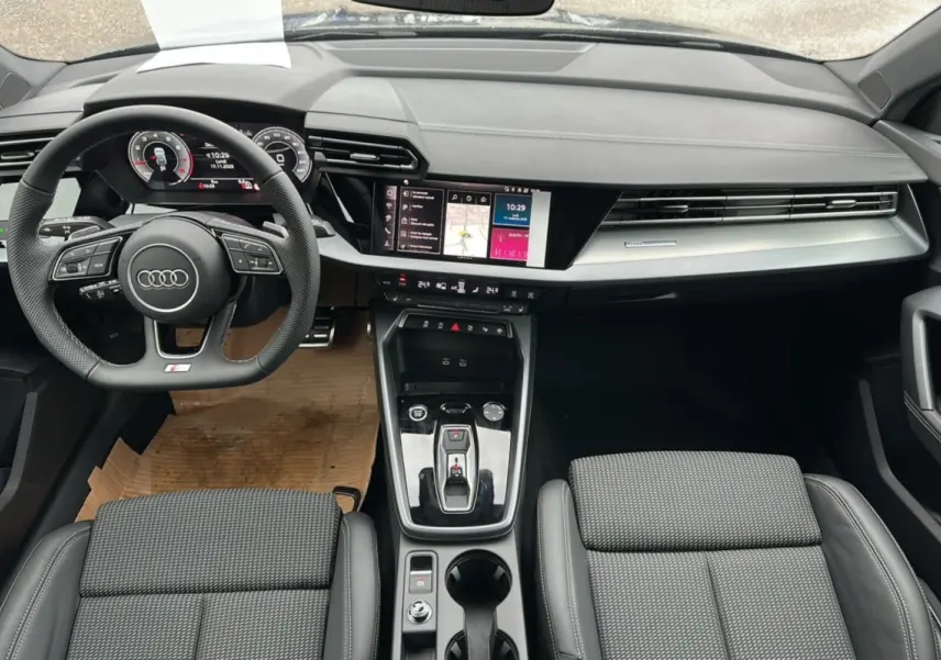 Vue intérieure de l'Audi A3 2025 TFSI 150 Hybrid S-Line, tableau de bord et console centrale modernes en noir.