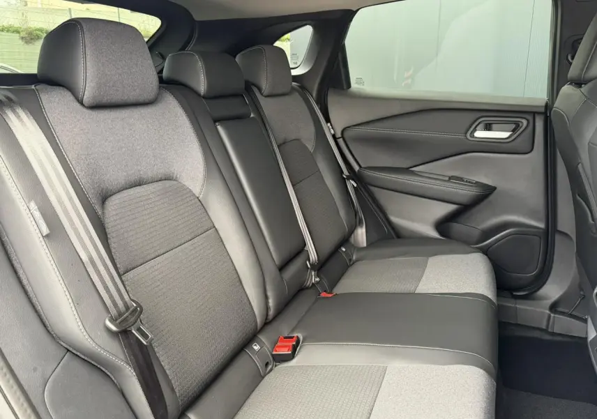 Vue intérieure côté droit des sièges arrière gris et noirs du Nissan Qashqai III e-Power 2025 avec ceintures et appuie-têtes visibles.