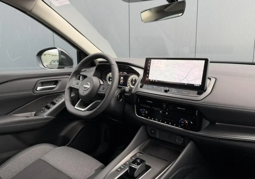Vue intérieure côté conducteur du Nissan Qashqai III e-Power 2025, tableau de bord moderne avec écran tactile et volant cuir noir.