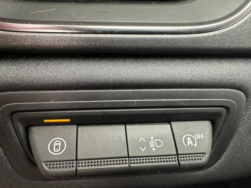 Gros plan sur les commandes noires du tableau de bord du Renault Captur 2025, avec indicateur orange allumé.