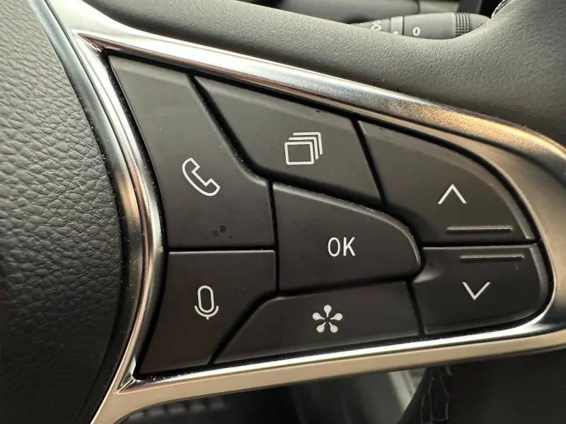 Gros plan sur les commandes noires du volant du Renault Captur 2025, avec boutons multifonctions et contour chromé.