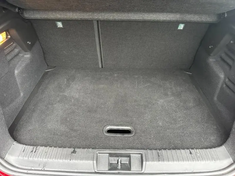 Coffre ouvert vu de face du Renault Captur 2025 Rouge Flamme/Noir Étoilé, montrant un espace de chargement vide et tapis noir.