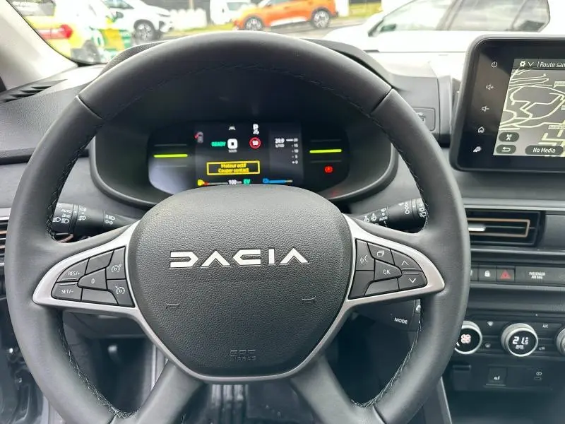 Vue rapprochée du volant noir du Dacia Jogger 2025 avec commandes intégrées et tableau de bord numérique en arrière-plan.