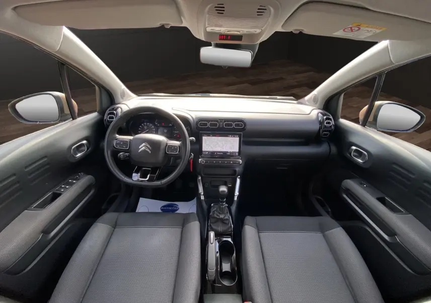 Vue intérieure avant du Citroën C3 Aircross gris platinium, mettant en valeur le tableau de bord et la console centrale avec boîte manuelle.