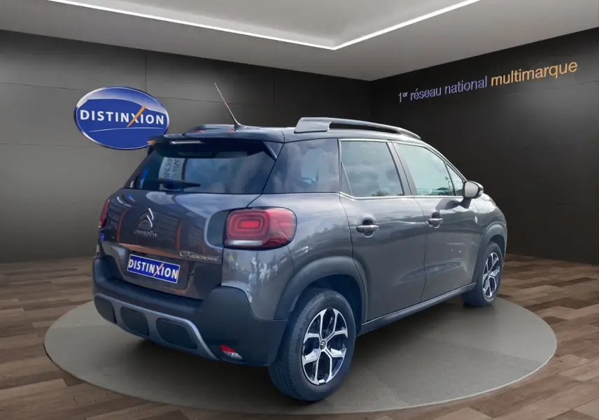 Vue 3/4 arrière droite d'un Citroën C3 Aircross gris platinium avec jantes alliage et caméra de recul visible.