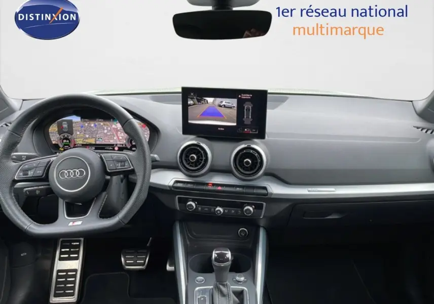 Vue intérieure avant de l'Audi Q2 35 2.0 TDI S-Line 2025 avec tableau de bord numérique et écran central affichant la caméra de recul.