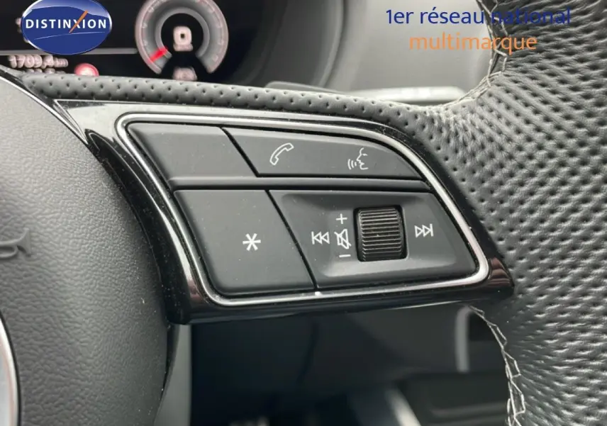 Gros plan sur les commandes noires du volant en cuir perforé de l'Audi Q2 35 2.0 TDI S-Line, intérieur noir.