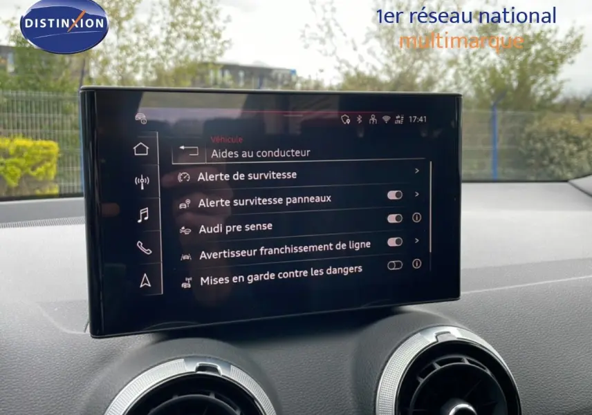 Écran central affichant les aides à la conduite dans l'Audi Q2 S-Line 2025, intérieur noir visible.