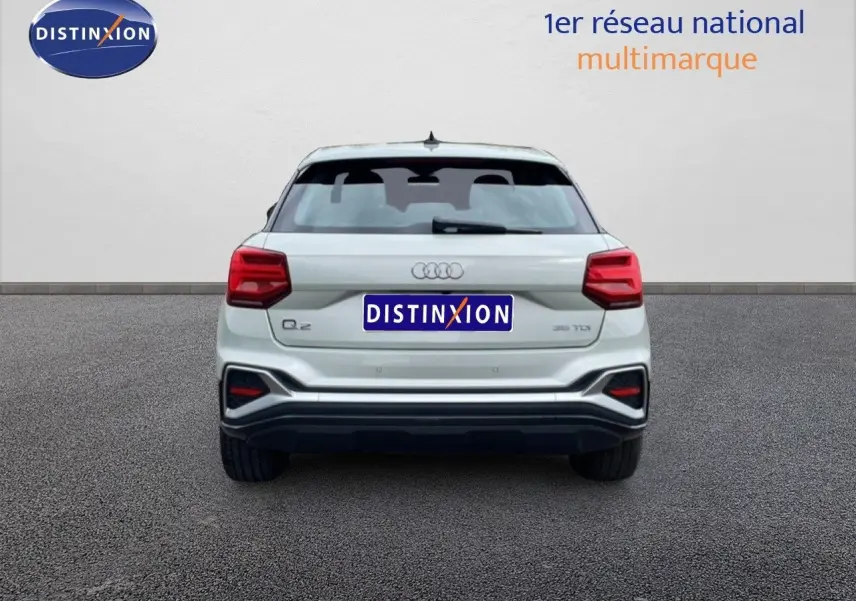 Vue arrière d'un Audi Q2 35 2.0 TDI argent rose métal, avec feux arrière rouges et logo distinctif au centre.