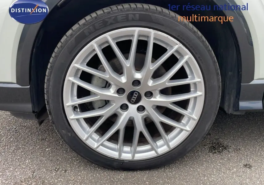 Gros plan sur la roue avant droite d’un Audi Q2 argent rose métal avec jante alliage multibranches.