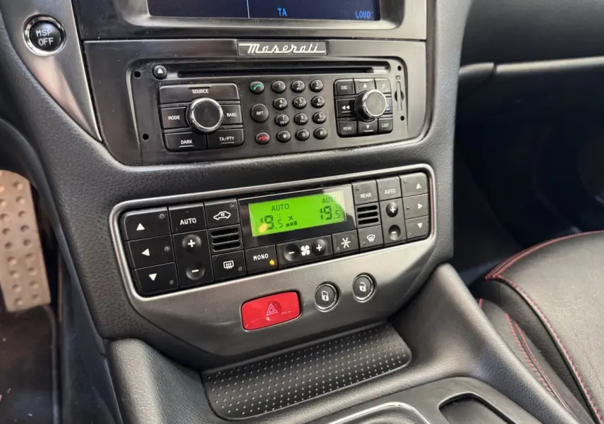 Vue rapprochée de la console centrale de la Maserati Granturismo S 4.7 2010, avec commandes climatisation et radio intégrées.