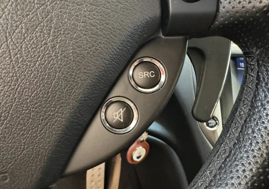 Gros plan sur les commandes audio au volant en cuir noir perforé de la Maserati Granturismo S 4.7 gris foncé de 2010.