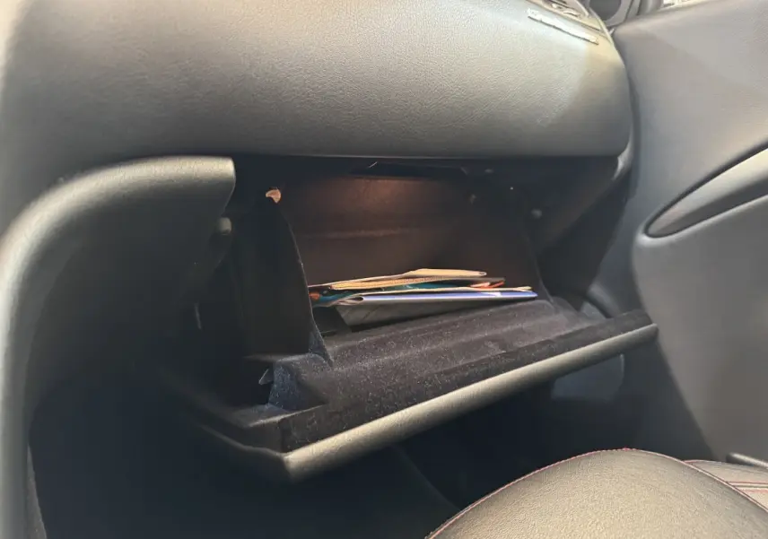 Vue intérieure côté passager de la boîte à gants ouverte d'une Maserati Granturismo S 4.7 gris foncé avec documents à l'intérieur.