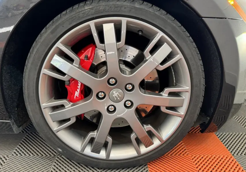Gros plan sur la roue avant droite grise d'une Maserati Granturismo S 4.7 2010 avec étrier de frein rouge marqué Maserati.