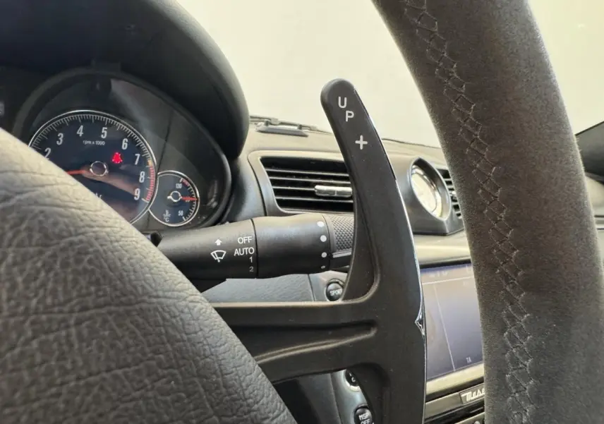Gros plan sur la palette de changement de vitesse droite en daim du volant d'une Maserati Granturismo S 4.7 gris foncé, tableau de bord visible.