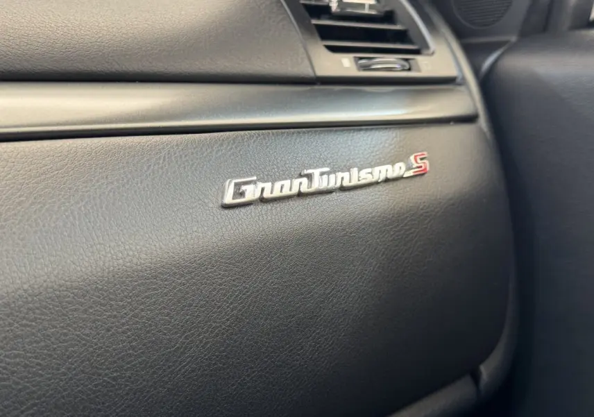 Gros plan sur le logo GranTurismo S argenté sur le tableau de bord noir intérieur d'une Maserati Granturismo S.