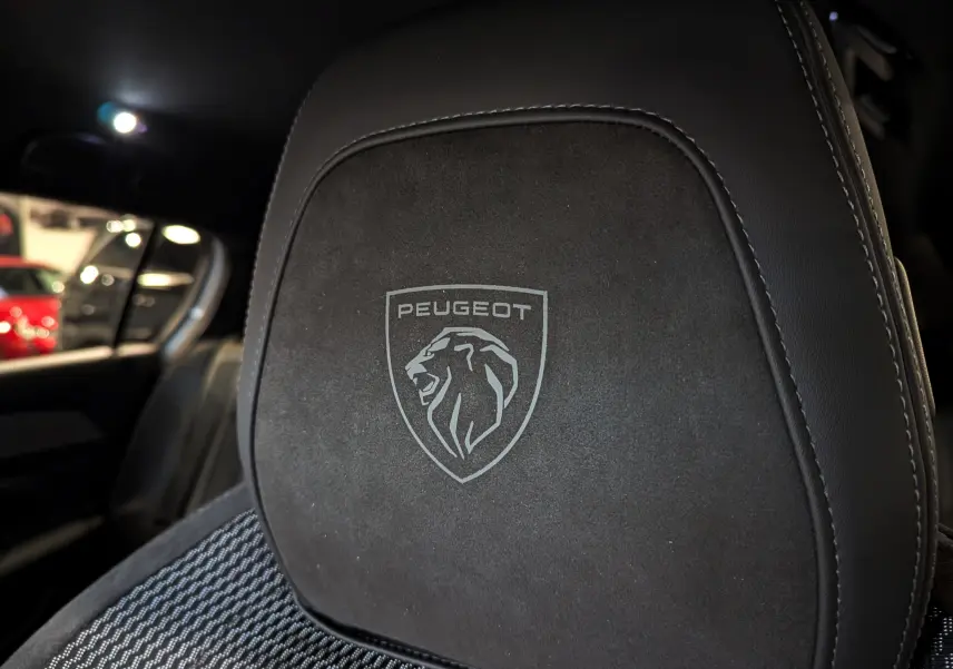 Gros plan sur l'appui-tête noir en alcantara avec logo Peugeot gravé, intérieur de la 308 GT 2024.