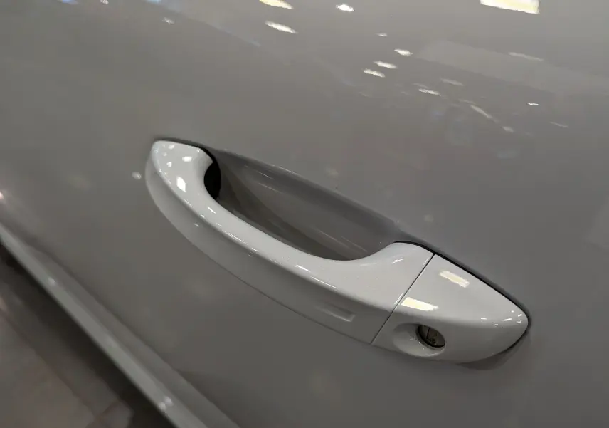 Poignée de porte blanche Okénite en gros plan sur le côté gauche d'une Peugeot 308 BlueHDi 130 GT 2024.