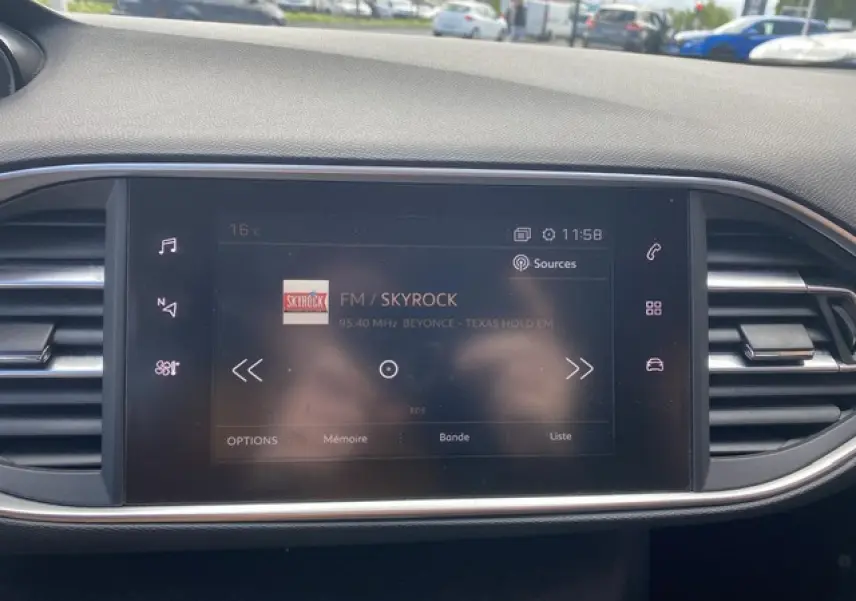 Écran tactile central de la Peugeot 308 SW 2018 affichant la radio FM Skyrock dans un intérieur gris sobre.