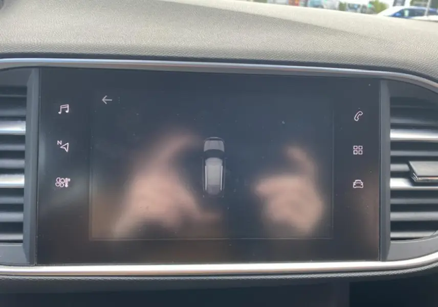 Écran tactile central de la Peugeot 308 SW 2018 affichant l'aide au stationnement dans un intérieur sombre.