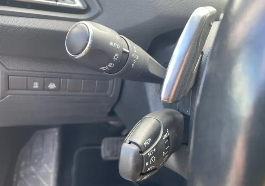 Gros plan sur les commandes de régulateur de vitesse et éclairage à gauche du volant d'une Peugeot 308 SW 2018.