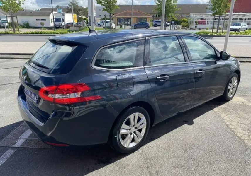 Peugeot 308 SW gris hurricane vue 3/4 arrière côté gauche, avec jantes alliage et feux arrière distinctifs.
