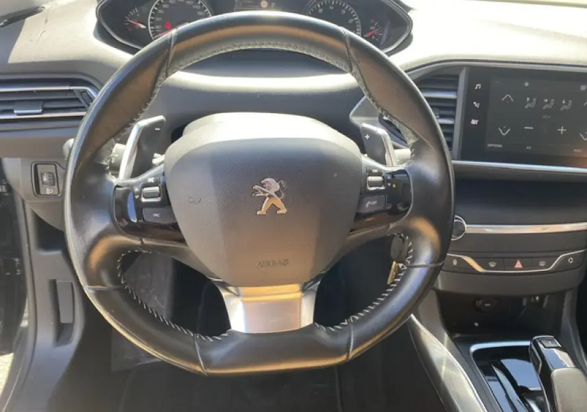 Vue rapprochée du volant cuir noir et du tableau de bord avec écran tactile de la Peugeot 308 SW gris Hurricane de 2018.