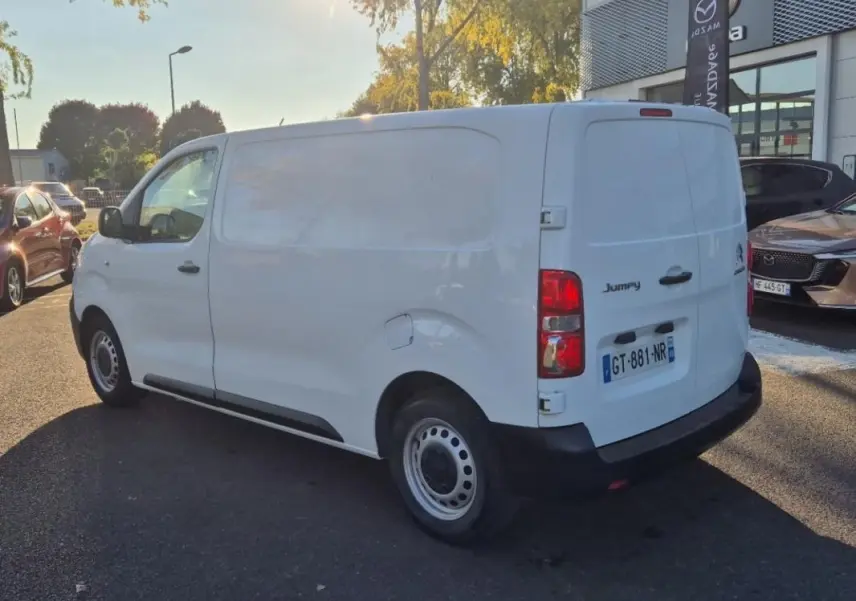 Vue 3/4 arrière droite d'un Citroën Jumpy blanc fourgon L2H1 avec hayon, stationné en extérieur au soleil.