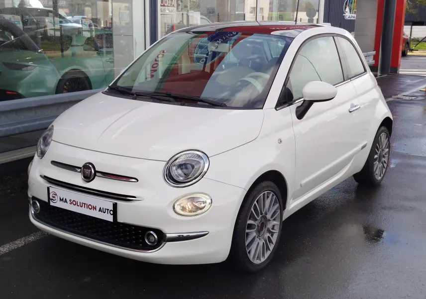 Vue 3/4 avant droite d'une Fiat 500 Lounge blanche Bossa Nova, avec jantes alliage et phares allumés.