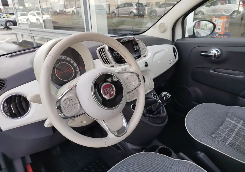 Vue intérieure côté conducteur de la Fiat 500 Lounge 2017 avec tableau de bord blanc Bossa Nova et volant cuir clair.