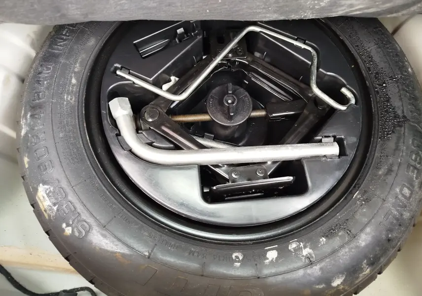 Gros plan sur la roue de secours et les outils de bord du coffre d’une Fiat 500 blanche, version Lounge 2017.