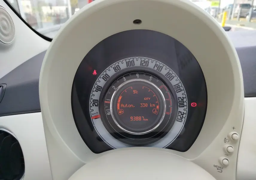 Gros plan sur le compteur central rond de la Fiat 500 blanche, affichant la vitesse et l'autonomie restante.