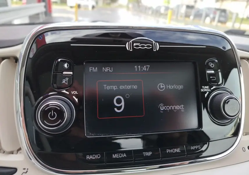 Gros plan sur l’écran tactile central noir brillant du tableau de bord de la Fiat 500 blanche, affichant la température extérieure.