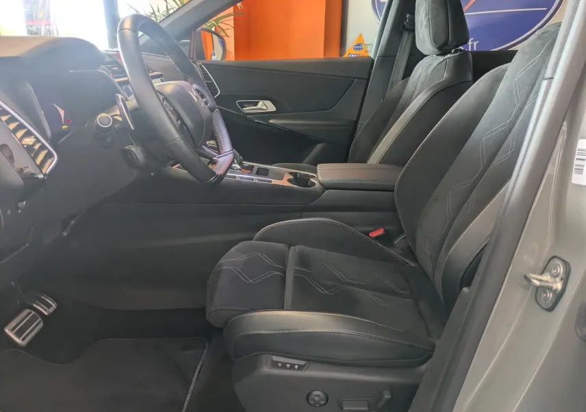 Vue intérieure côté conducteur du DS7 gris laque 2025, sièges en Alcantara noir avec coutures apparentes et console centrale moderne.