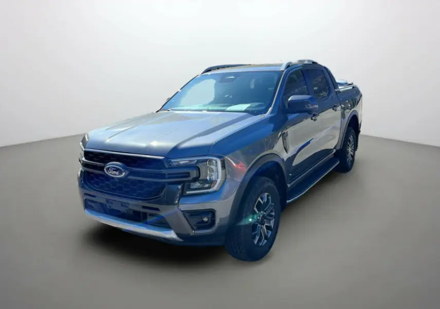 Ford Ranger 2025 gris carbone en 3/4 avant droit, avec calandre noire et jantes alliage distinctives Wildtrak Plus.