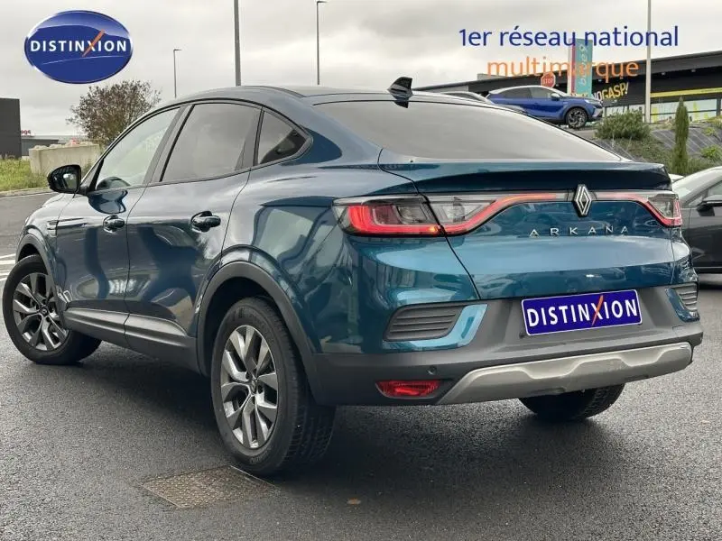 Vue 3/4 arrière droite d'un Renault Arkana bleu Zanzibar 2025 avec feux arrière reliés par un bandeau lumineux rouge.