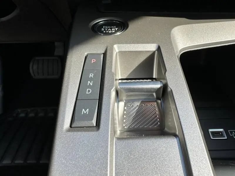 Gros plan sur la console centrale grise Artense avec levier de boîte automatique et bouton start/stop du Peugeot 308 2025.