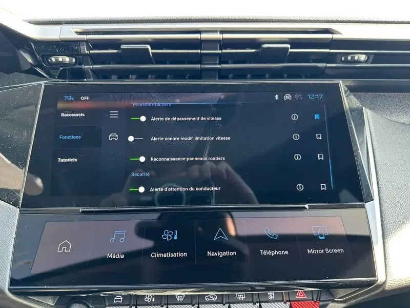 Écran tactile central du tableau de bord de la Peugeot 308 2025, affichant les alertes de sécurité et fonctions multimédia.