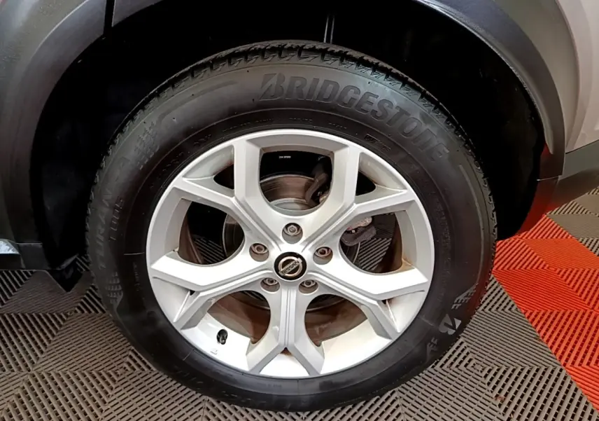 Gros plan sur la roue arrière droite du Nissan Juke gris clair, avec jante argentée et pneu Bridgestone visible.